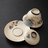 Set of ceramic gaiwan, saucer, and lid with floral patterns on a dark background