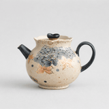 Ceramic teapot with floral design on a light gray background